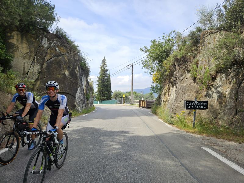 Zwei Radfahrer lachend am Schild Col de Calaison, 450 m