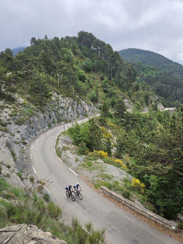 Blick von oben auf eine Bergstraße am Kalkfelsen, zwei Radfahrer nebeneinander