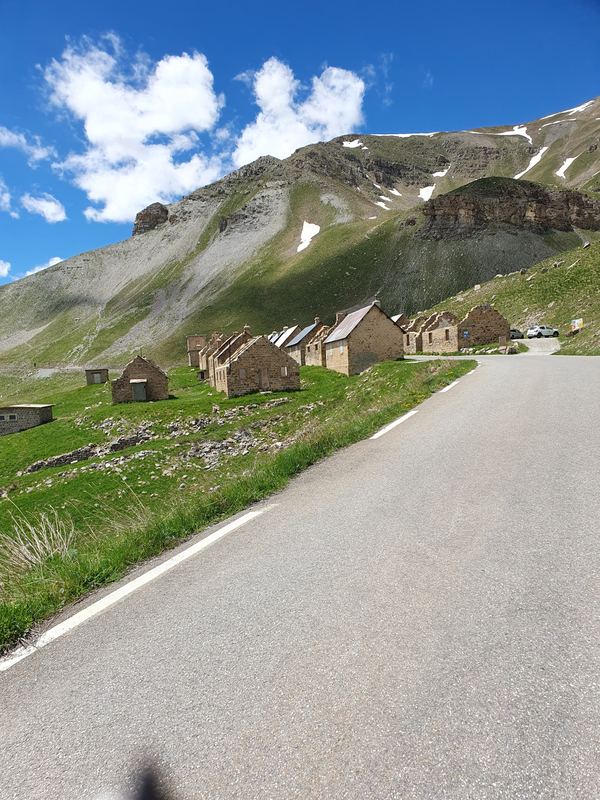 Steinbaracken des Camp des Fourches an der leeren Straße, dahinter Geröll und Schneefelder