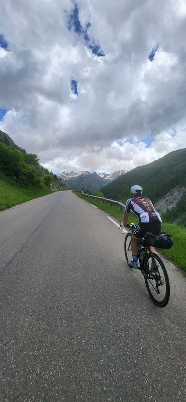 Markus allein auf der breiten, leeren Passstraße unter großen Wolken