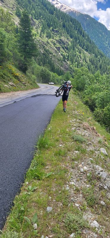 Radfahrer trägt sein Rad auf dem Grünstreifen neben dem frischen Asphalt